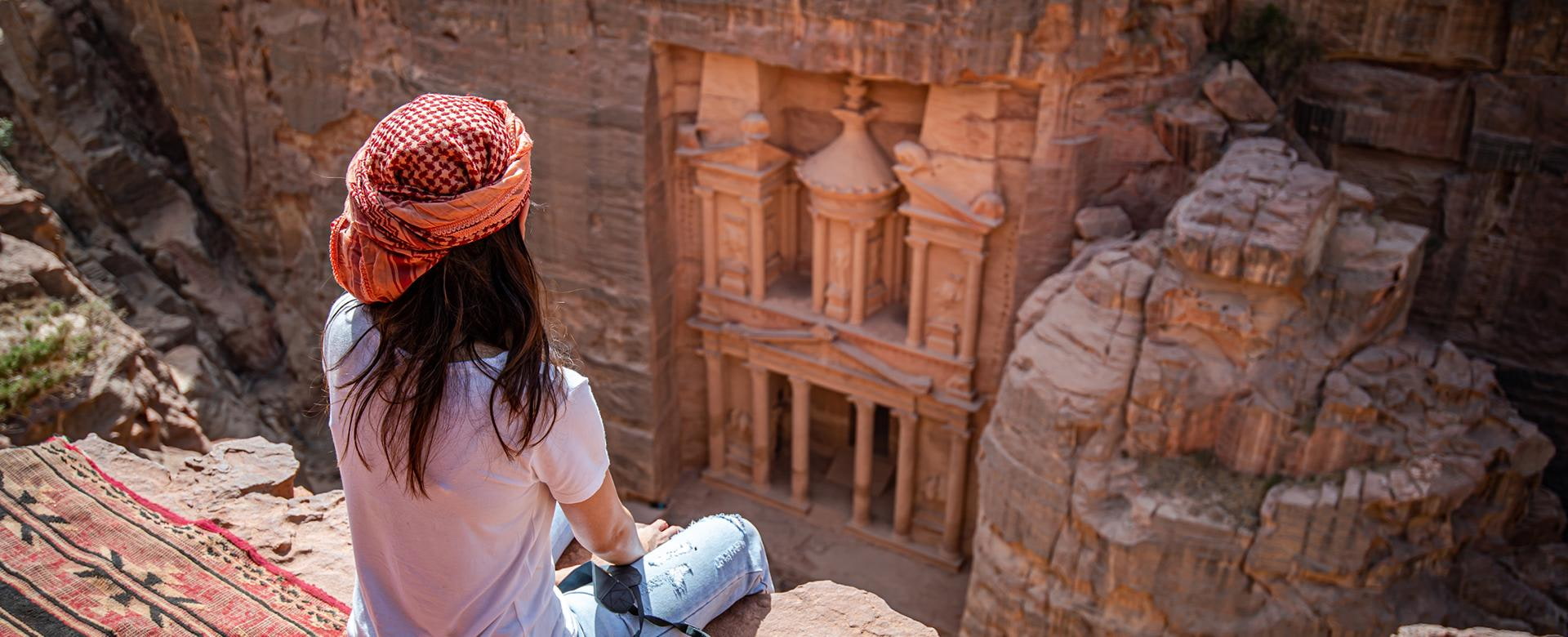 Frau sitzt vor dem UNESCO Weltkulturerbe Petra in Jordanien